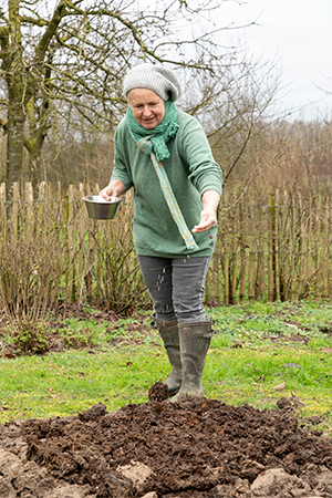 Vrouw verspreid zaadjes over compost